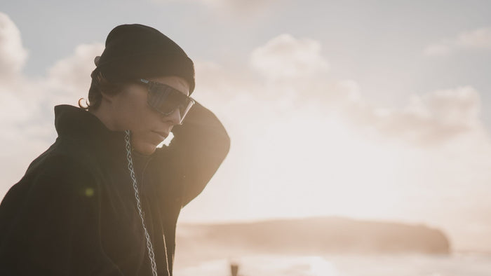 Person wearing Smith sunglasses, standing in front of the ocean while the sun sets. 
