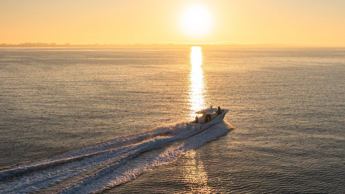 Image au lever du soleil d’un bateau de pêche traversant l’eau